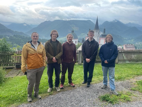 Group photo with a hilltop church and mountains behind